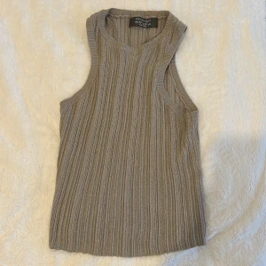 Beige ribbad linnetopp från Primark - Säljer en beige ribbad linnetopp från Primark i storlek XS. Toppen är ärmlös med rund halsringning och har en snygg stickad struktur som ger en cool och avslappnad vibe. Perfekt att matcha med jeans eller kjol för en enkel men trendig look.