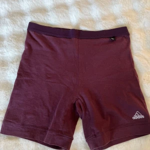 Vinröda träningsshorts från Adidas - Snygga vinröda shorts från Adidas, står att det är i stl L men de är konstiga i storleken då de passar mig bra som har xs-s.De är gjorda i mjuk bomull, perfekt för träning. Adidas-loggan är broderad i vitt på benet och de har en clean, slim passform som sitter skönt mot kroppen. De är i väldigt bra skick då de knappt är använda. Pris kan diskuteras. Hör av er om frågor!❤️