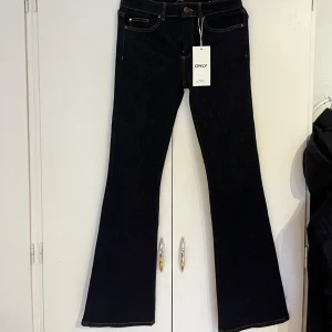 Mörkblå bootcut jeans från ONLY - Snygga mörkblå jeans från ONLY med klassisk bootcut-modell och kontrastsömmar. Jeansen har fem fickor, normal passform och är tillverkade i ett stretchigt bomullsmaterial som sitter skönt hela dagen. Perfekta till sneakers eller boots. Helt nya, så oanvända och köpta bara för någon vecka sen. Org. Pris 549kr