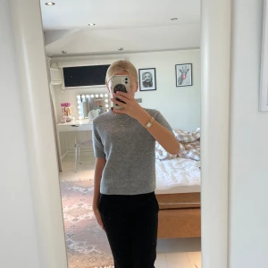 Grå stickad kortärmad tröja från Zara - Supermjuk grå stickad tröja från Zara med korta ärmar och rund hals. Perfekt basic att ha i garderoben, funkar lika bra till jeans som till kostymbyxor. Materialet är ullblandning som känns lyxigt och skönt mot huden.