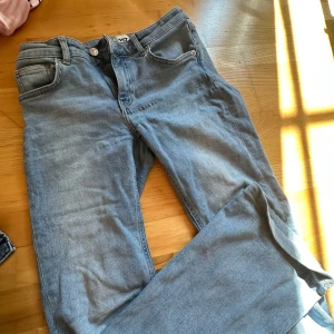Ljusblå bootcut jeans från 157 - Säljer ett par ljusblå jeans från 157 i modellen Low Boot. Jeansen har klassisk femficksdesign, normal passform och är tillverkade i mjukt bomullstyg med lite stretch. Perfekta för dig som gillar bootcut och vill ha en avslappnad look. Jeansen är uppsydda och går till anklarna på mig som är 165cm