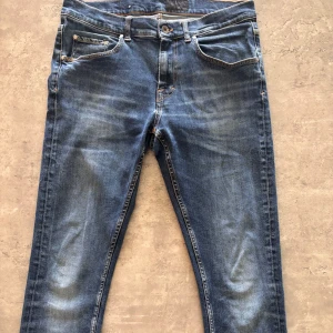 Tiger Of Sweden Jeans - Säljer ett par blå jeans med slim passform och klassisk femficksdesign. Jeansen har snygga slitningar och en något mörkare tvätt. Tillverkade i stretchigt jeanstyg för skön känsla och bra passform. Perfekta till alla outfits. Jeansen är 33/34 men skulle säga att de är mindre. Inga defekter! Har du funderingar, hör av dig!