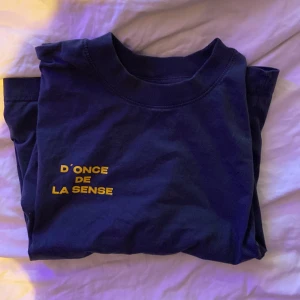 D’once de la Sense t shirt  - Blå t-shirt i bomull med tryckt gul text 'D'ONCE DE LA SENSE' på bröstet. Knappt använd. Skriv vid minsta funderingar!