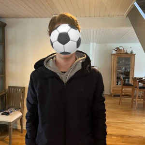 Svart vindjacka från Calvin Klein Jeans - Snygg svart vindjacka från Calvin Klein Jeans i storlek M. Jackan har huva, dragkedja framtill och en diskret logga på bröstet samt patch på ärmen. Perfekt för dig som gillar stilrena och funktionella plagg. Passformen är normal och materialet känns lätt och smidigt.