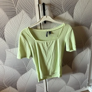 Ljusgrön ribbad topp från H&M - Snygg ljusgrön ribbad topp från H&M med korta ärmar och fyrkantig urringning. Croppad modell som passar perfekt till det mesta. Enkel men trendig stil med diskreta detaljer längs halsringningen.