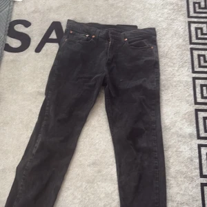 Svarta Levi's 501 jeans straight fit - Säljer ett par svarta Levi's 501 jeans med klassisk straight fit. Jeansen har fem fickor, knapp och dragkedja framtill samt den ikoniska läderpatchen bak. Tillverkade i bomull och passar perfekt till en avslappnad streetstil.