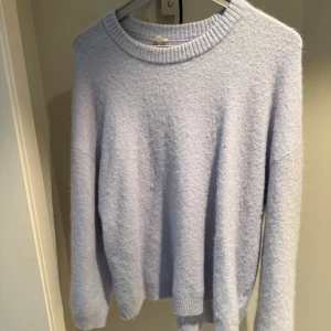 Ljusblå stickad tröja med rund hals ARKET - Supermjuk och fluffig ljuslila stickad tröja med rund halsringning och långa ärmar. Perfekt för lager-på-lager och chill dagar. Ribbstickade muddar vid ärmslut och nederkant ger en snygg passform.