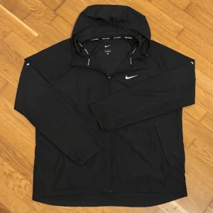 Nike miler (Svart storlek L)  - Nike miler svart vindjacka. Knappt använd, ca 1 månad. Storlek L. Finns att hämta i Hässelby gård/Stockholm. 