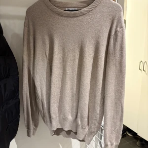 Beige stickad tröja från Zara - En stilren beige stickad tröja från Zara med rund halsringning och långa ärmar. Tröjan har en klassisk passform och ribbade muddar vid ärmslut och nederkant. Perfekt för lager-på-lager och enkel att matcha med jeans eller kjol.