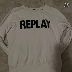 Vit sweatshirt från Replay - Vit sweatshirt från Replay med svart tryck över bröstet. Klassisk rund halsringning och långa ärmar. Mjuk och skön bomullskänsla, perfekt för en chill look. Passar dig som gillar stilrena och enkla plagg med tydlig logga.