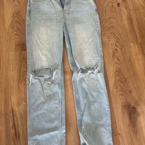 Ljusblå ripped jeans från Gina Tricot - Säljer ett par ljusblå jeans från Gina Tricot med raka ben och stora slitningar vid knäna. Storlek 38