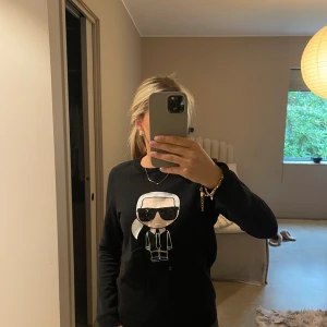 Svart Karl Lagerfeld sweatshirt - Svart sweatshirt från Karl Lagerfeld med ikonisk Karl-figur framtill. Tröjan har paljettdetaljer på solglasögonen och är långärmad med rund hals. 