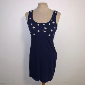 Mörkblå stjärnmönstrad klänning HM - Mörkblå kortklänning från Divided (H&M) med vita stjärnor upptill. Ärmlös modell med rundad urringning och figurnära passform. Storlek 36
