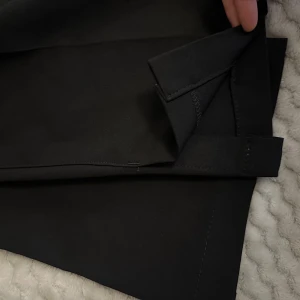 Svarta kostymbyxor från Bik Bok - Svarta kostymbyxor från Bik Bok i klassisk rak modell. Byxorna har hällor för bälte, diskreta sidfickor och stängs med dragkedja och hake. Snyggt skräddade ben och stilren look, perfekta till en dressad outfit. Använd bara några gånger. Längden är perfekt för de som är 158.