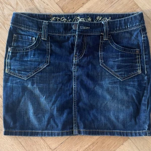 Mörkblå jeanskjol från Esprit - Snygg mörkblå jeanskjol från Esprit med klassiska fickor fram och bak, bälteshällor och kontrastsömmar. Modellen är kort och har en  passform som sitter snyggt på höften. 