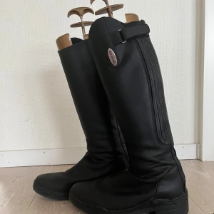 Svarta ridstövlar från Horsehead - Snygga svarta ridstövlar från Horsehead i skinn med klassisk design och diskret spänndetalj upptill. Storlek 35.
