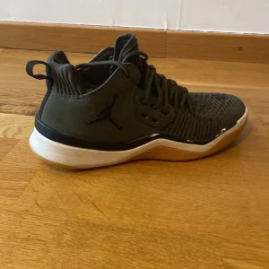 Svarta Jordan sneakers med stickad ovandel - Säljer ett par svarta Jordan sneakers med stickad ovandel och vita sulor. Skorna har snörning, rund tå och en cool, sportig look. Ovandelen är i syntetmaterial och mesh för extra andningsförmåga. Perfekta för dig som gillar streetstyle och basketinspirerad design.