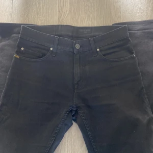 Svarta jeans från Tiger of Sweden - Snygga svarta jeans från Tiger of Sweden med klassisk femficksdesign och diskret logga på bakfickan. Jeansen har raka ben och normal passform, perfekta till sneakers eller boots. Materialet är mjukt och följsamt för en bekväm känsla hela dagen.