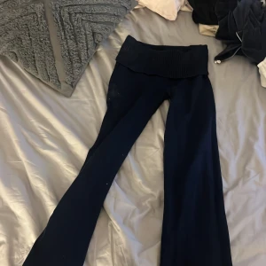 Mörkblå ribbade stickade byxor - Säljer ett par mörkblå stickade byxor med bred ribbad midja. Byxorna har en rak och något utsvängd passform, perfekta för en chill och avslappnad stil. Materialet är mjukt och stretchigt, vilket gör dem riktigt bekväma att ha på sig.