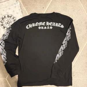 Chrome hearts - Svart långärmad tröja från Chrome Hearts med vita tryck längs båda ärmarna och logga på bröstet.  Den är använd men inga skador på den, storleken är L men rekommenderar mindre storlek för bättre passform. Priste kan diskuteras och skriv gärna för mer information!
