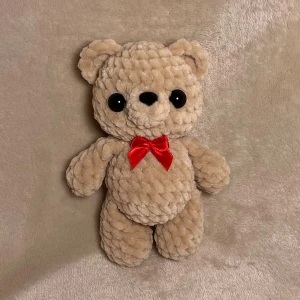 Virkad nallebjörn med rosett - En virkad liten nallebjörn med rosett. Den är mjuk och stoppad med fyllnadsvadd! Och har Säkerhetsögon, och den är virkad av mig!