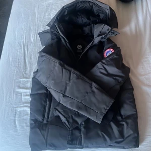 Svart dunjacka från Canada Goose - Säljer en Silver grå dunjacka från Canada Goose med klassisk logga på ärmen. Jackan har huva, långa ärmar och är riktigt tjock och varm. Perfekt för kalla vinterdagar och har en stilren look som funkar till allt. Fylld med dun och har snygga detaljer.‼️KAN SKANNAS‼️ ‼️FRAKTAS SAMMA DAG ELLER DAGEN EFTER‼️‼️PRUTBART‼️