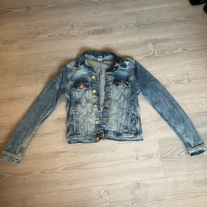 Blå jeansjacka från H&M - Snygg klassisk jeansjacka i blå tvätt från H&M, storlek 36. Jackan har långa ärmar, bröstfickor med knappar och framfickor. bronsfärgade knappar framtill och på fickorna ger en cool touch. Perfekt att slänga över en hoodie eller t-shirt. Väldigt slim och liten för att vara storlek 36, jag använde den när jag gick i sjunde klass, vill att ni ska få ett hum om hur liten den är😅💛