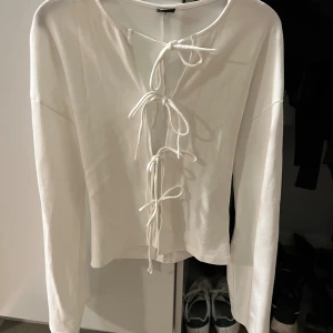 Vit tröja med knytning  - Säljer den här fina tröjan med snörning där framme. Aldrig använd! I gott skick.