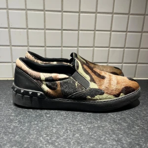 Valentino Loafers  - Tjenare tjenare allihopa just nu så säljer mina as snygga Valentino loafers med camouflage-mönster i brunt, grönt och svart. Ovandel i pälsliknande material och svarta läderdetaljer vid hälen. skorna är mycket fint skick och det är så klart äkta. Jag tar gärna emot byten om du bor i Stockholm. Har du några ytterligare frågor bara att höra av dig? Med vänliga hälsningar Oscar