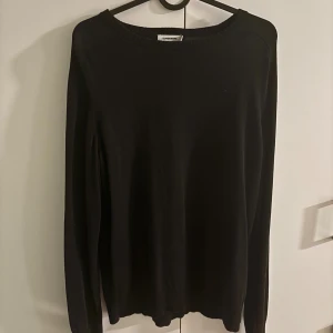 Svart långärmad tröja J.Lindeberg - En stilren svart långärmad tröja från J.Lindeberg. Tröjan har rund halsringning och är tillverkad i ett mjukt material som passar perfekt till lager-på-lager. Enkel och klassisk design som funkar till det mesta.