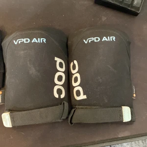 Svarta POC VPD Air ben och armbågsskydd  - Svarta skydd från POC, modell VPD Air, med vit logga och justerbara kardborreband. De är designade för att ge extra skydd och komfort vid träning eller sport. Materialet är syntetiskt och slitstarkt, perfekt för dig som vill ha både stil och funktion. Använt en till två gånger men ägd dem i 4 år. Ny pris är ungefär 1000 totalt.