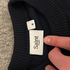 Svart tröja från Saint Tropez M - En stilren mörkblå tröja från Saint Tropez i storlek M. Tröjan har rund halsringning, långa ärmar och breda ribbade muddar vid ärmslut och nederkant. Perfekt för dig som gillar en enkel och klassisk look.