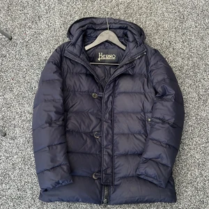 Herno vinterjacka  - Säljer nu en sjukt snygg herno jacka! En väldigt klassisk look. Avtagbar luva! Hör grage! Size 46 motsvarar S. Modellen är lång på längden. Bra skick men finns några enstaka tecken på användning. Hör av dig vid minsta fundering 🤩