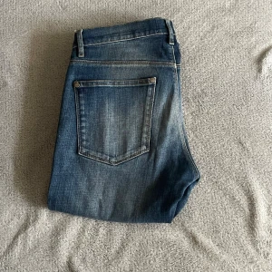 Blå jeans från Acne Studios - 👖✨ Snygga Acne Studios jeans – perfekt mix av stil och komfort! Dessa klassiska jeans från Acne Studios har en vacker mellanblå tvätt med naturliga slitningar som ger en avslappnad men trendig look. 👌 Modellen är smal utan att sitta för tight – perfekt för både vardag och utekväll.  💙 Kvaliteten känns redan vid första beröring, och passformen gör att du alltid ser välklädd ut. Matcha med en vit t-shirt för en tidlös look, eller dressa upp med en skjorta – funkar till allt! 🌿