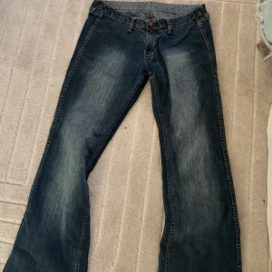 Blå bootcut jeans med slitningar - Snygga blå jeans med bootcut-modell och lätt slitna detaljer framtill. Klassisk femficksdesign och kontrastsömmar. Jeansen har normal passform och är tillverkade i jeansmaterial. 