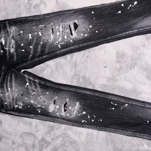 Svarta Dsquared2 jeans med slitningar - Svarta jeans från Dsquared2 i slim fit med coola slitningar och vita färgstänk. Jeansen har klassisk femficksdesign, knappgylf och tydlig Dsquared2-logga vid fickan. Materialet är jeans och de har en modern, edgy vibe.