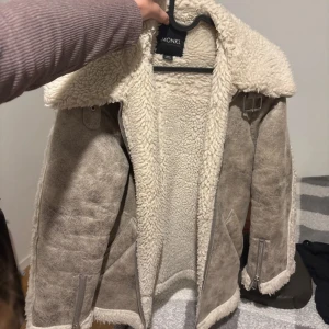 Beige teddyjacka från Monki - Säljer en beige teddyjacka från Monki med stora kragar och mysigt foder i teddy. Jackan har dragkedjor vid ärmslut och fickor, samt snygga spänndetaljer vid kragen och nederkanten. Perfekt för kalla dagar 🩷storlek XXS men är ungefär en XS/S