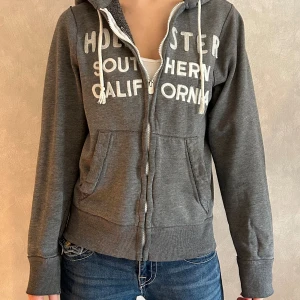 Zip-up huvtröja Hollister - En zip-up hoodie med luva från Hollister. Storlek S. Defekter förekommer (se bild 3)! Fint skick, utom att dragkedjan har blivit något missfärgad. Skriv vid frågor/ funderingar/ mått!💖PRISET ÄR ALLTID DISKUTERBART!😄
