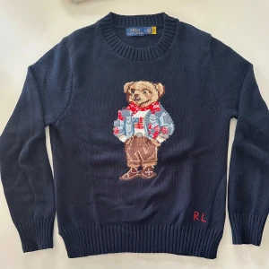 Mörkblå stickad tröja Ralph Lauren Polo Bear  - Mörkblå stickad tröja från Polo Ralph Lauren med ikoniska Polo Bear-motivet framtill. Perfekt till vinter o höst! Storlek M (men är mer som en S). Hör gärna av er vid minsta fundering