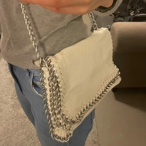 Vit läder väska tiamo - Perfekt vardaglig väska till skolan eller jobbet. Två fickor med dragkedja samt 2 mindre fack på sidorna inuti väskan. Den är 27 cm x 17 cm x 5 cm ungefär Använd fåtal gånger. 