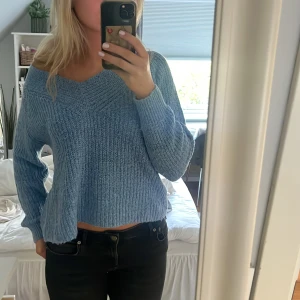 Blå stickad tröja från Pigalle - Mysig blå stickad tröja från Pigalle med v-ringning och lång ärm. 
