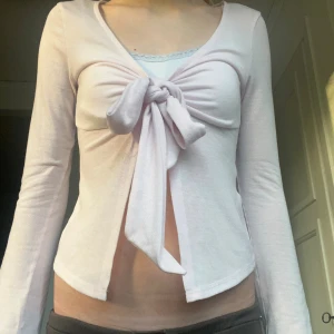 Söt Ljusrosa långärmad topp från Gina Tricot!💗 - Supersöt ljusrosa långärmad topp från Gina Tricot med v-ringning och stor knytrosett framtill. Modellen är croppad upptil och är lite lösare nertill! 