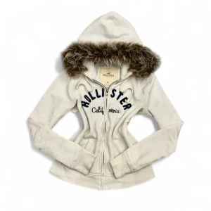 Hollister Fur Hoodie - ✨ Säljer en unik fur hoodie från märket (Hollister) ✨ Pälsen är ditsatt i efterhand för en personlig och trendig look. Storleken är (M), men den kan även passa (S) beroende på önskad passform. Eftersom plagget är second hand kan mindre defekter jag missat förekomma! – se gärna min bio för mer info.  💎 Priset är fast och ej förhandlingsbart.  Tvättråd: Handtvätta i ljummet vatten, var försiktig med pälsen, alternativt tvätta tröjan i en tvättpåse i tvättmaskinen 30-40grader. Undvik torktumlare. 