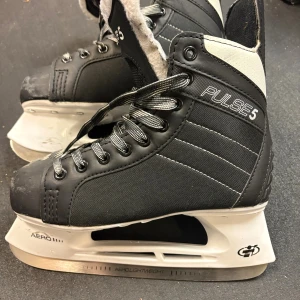Svarta Pulse 5 skridskor med snörning - Säljer ett par svarta Pulse 5 skridskor med kraftig snörning, robusta stålblad,  Aero Lightweight-blad. Storlek 37