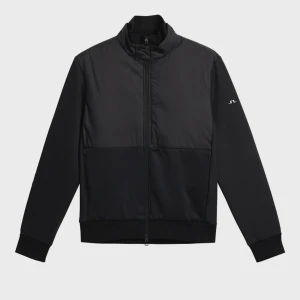 Svart vindjacka från J.Lindeberg - Snygg svart vindjacka från J.Lindeberg med minimalistisk design och diskret logga på ärmen. Jackan har hel dragkedja, hög krage och ribbade muddar. Materialet är lätt och känns sportigt, perfekt för blåsiga dagar. Klassisk passform och stilren look.