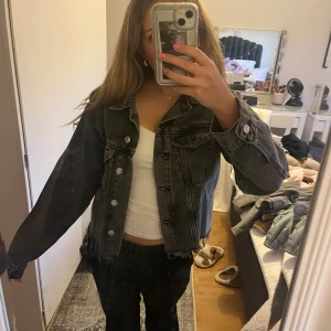 Grå  jeansjacka - Säljer en grå jeansjacka med klassisk krage och silverfärgade knappar framtill. 