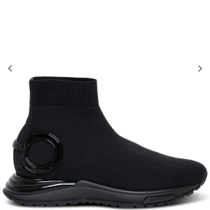  Salvatore Ferragamo sock sneakers - Snygga svarta sockboots med rund tå och platt sula från Salvatore Ferragamo. Skorna är stickade i syntetmaterial och har en ribbad kant vid ankeln. På hälen finns en blank svart logodetalj som ger en cool touch. Perfekt för dig som gillar stilrena och moderna sneakers. Använd endast ett fåtal gånger, dem är hela och rena. Kvitto finns