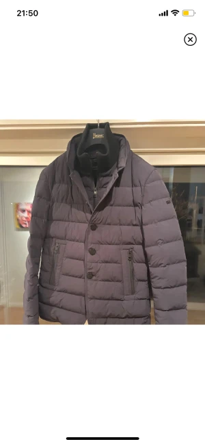 Mörkblå dunjacka från Duno - Snygg mörkblå dunjacka från Duno med quiltad design, tre knappar framtill och dragkedjor på fickorna. Jackan har hög krage och är tillverkad i lätt, stretchigt och vattenavvisande material med bra andningsförmåga. Perfekt för kalla dagar. Pris går att diskuteras vid snabb affär:)