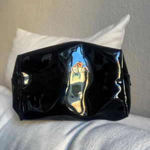 Svart necessär från CAIA - Snygg svart necessär från CAIA med glansig finish och stilren form. Helt ny, aldrig använd! 