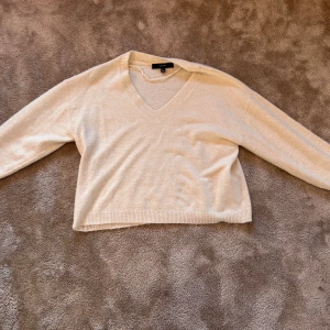 Beige stickad V-ringad tröja Vero Moda - Mysig beige stickad tröja från Vero Moda i storlek S. Tröjan har en snygg V-ringning, ribbade muddar och lång ärm. Perfekt för att hålla sig varm och ändå se chill ut. Passar dig som gillar enkel och clean stil.